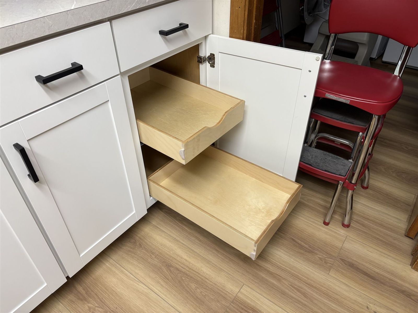 Two pull-out shelves extended from white shaker cabinets at standing height